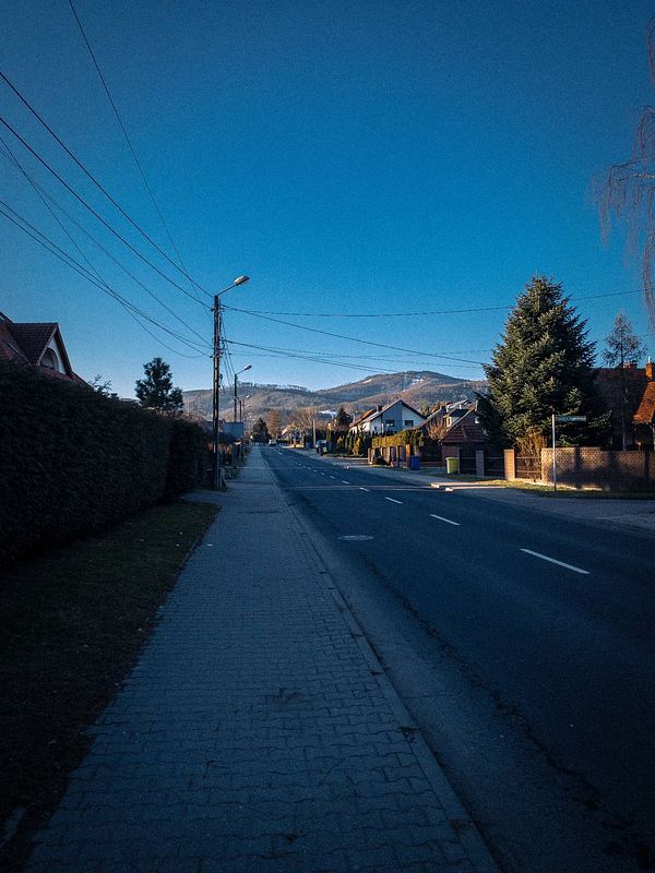A quiet suburban street under a clear blue sky, ideal for a morning walk.