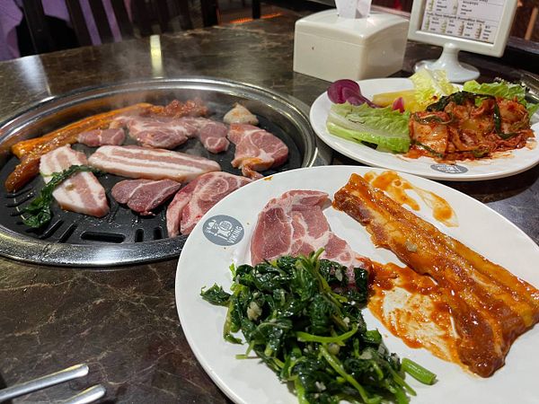 A Korean BBQ setup featuring various meats and side dishes.