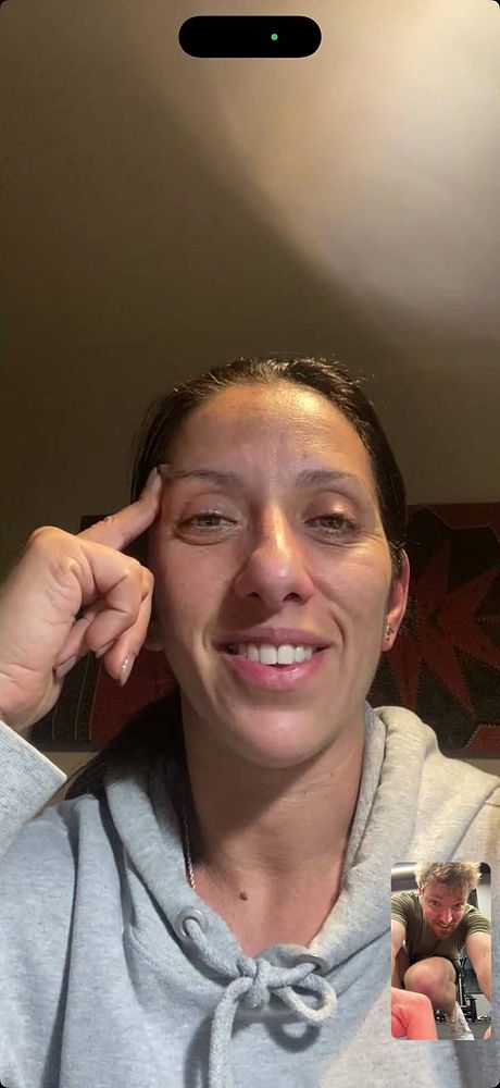 An image of a modern gym interior featuring various exercise machines and equipment along a large window with a view outside.