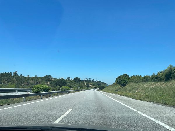 A scenic view of a highway leading towards Porto, Portugal, under a clear blue sky.