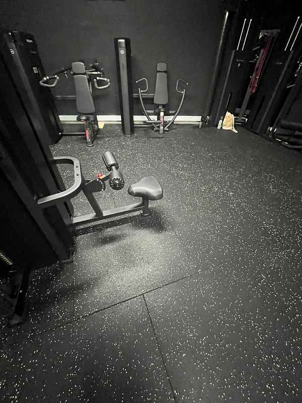 A dimly lit gym area featuring various exercise machines and equipment.