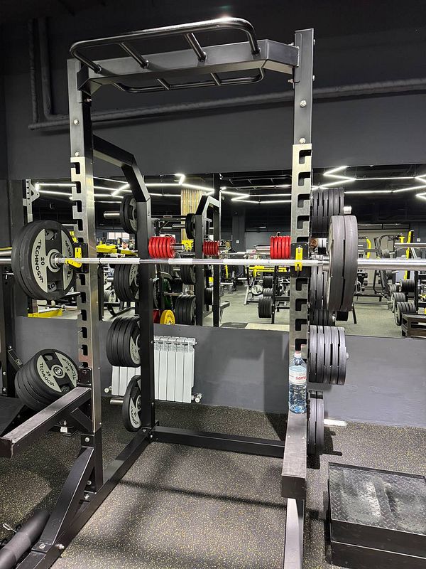 A well-equipped gym area featuring a squat rack with weights.