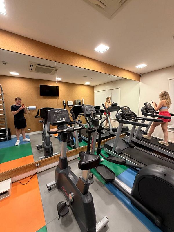 A person dressed in athletic clothing poses on a railing with a cityscape background during sunrise or sunset.