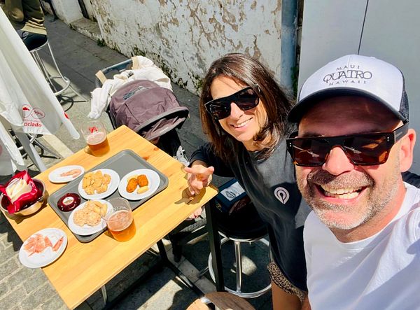 A cheerful couple enjoys tapas and drinks at an outdoor table.