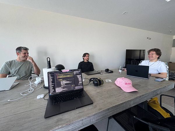 A group of three individuals is engaged in a coworking session at a modern workspace.