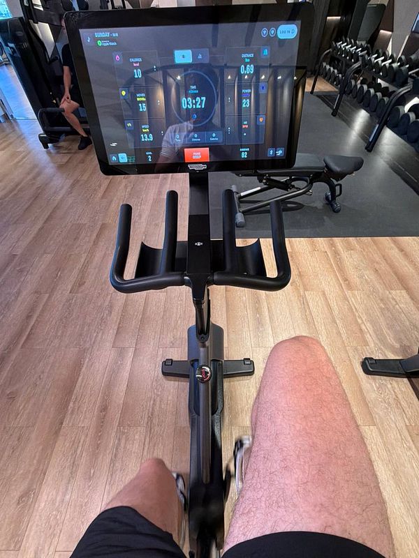 A person wearing gym attire working out on a stationary bike in a gym setting.