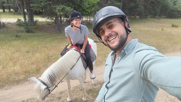 A couple enjoys horseback riding in a natural setting.