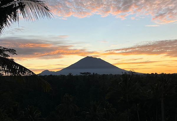 A breathtaking sunrise over a mountainous landscape surrounded by lush greenery.
