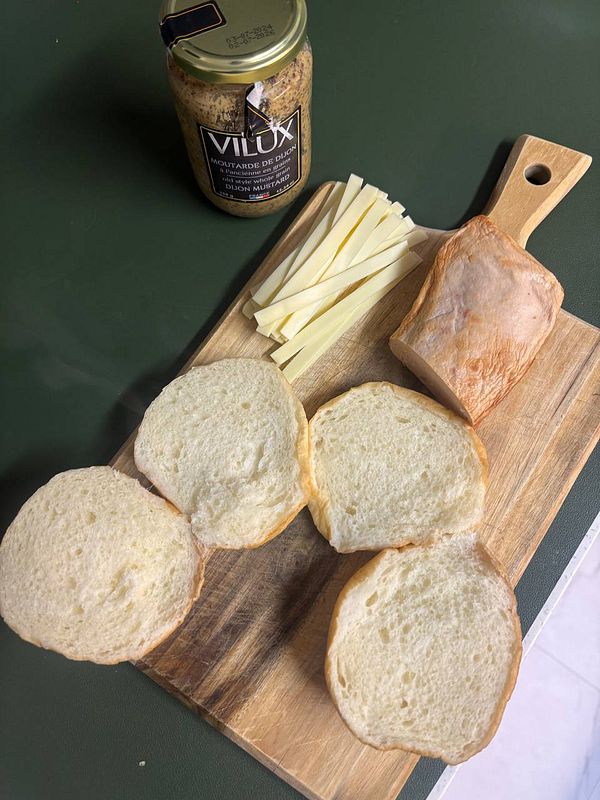 Close-up of sliced Fleischkäse and cubed cheese on a white plate with a fork.