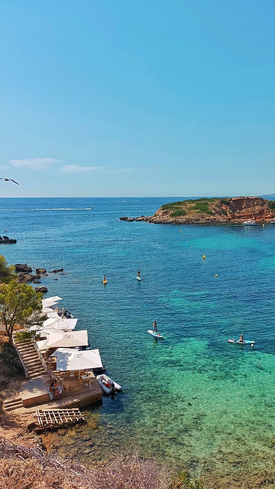 A picturesque coastal scene featuring clear turquoise waters and people enjoying water activities.