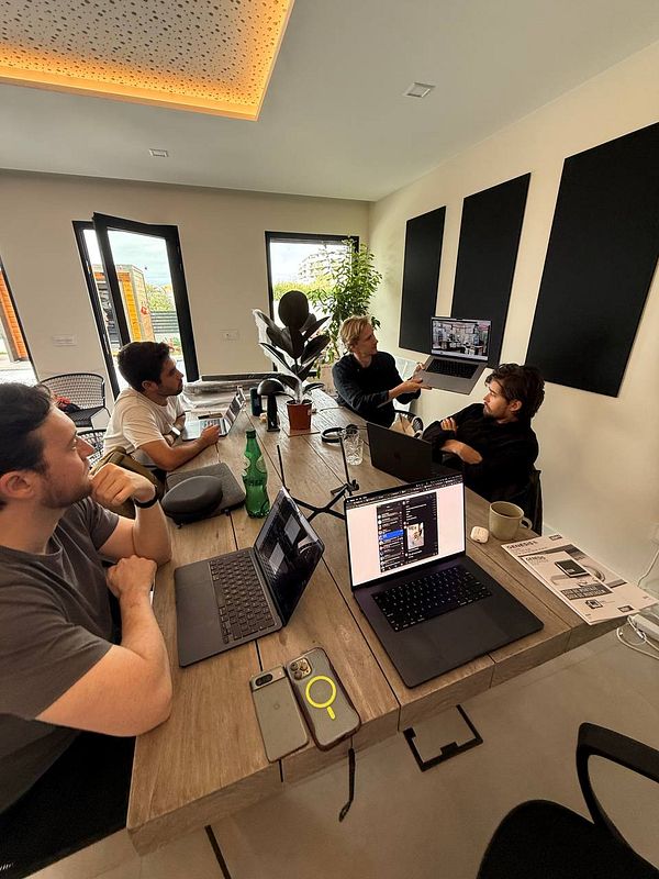A group of four individuals is engaged in a collaborative work session in a modern coworking space.