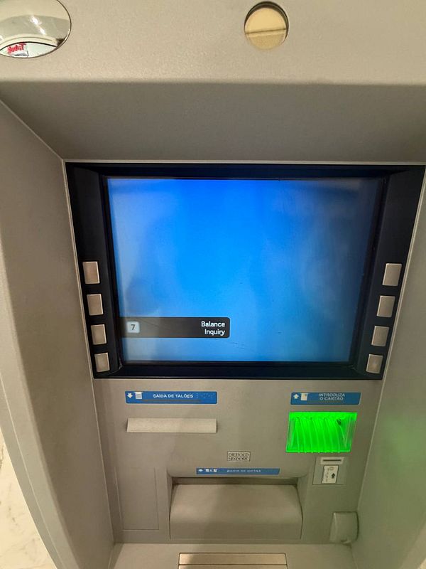 A photograph of two ATM machines situated outdoors against a stone wall in Portugal.