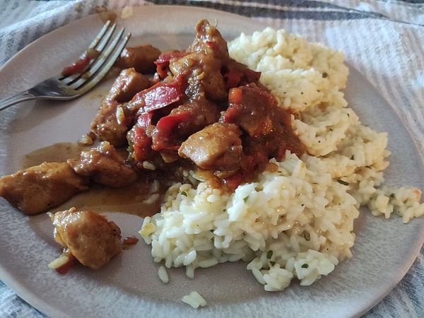 A plate of chicken and rice with a fork beside it.