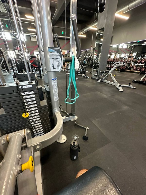 The image captures a gym setting with workout equipment and a water bottle.