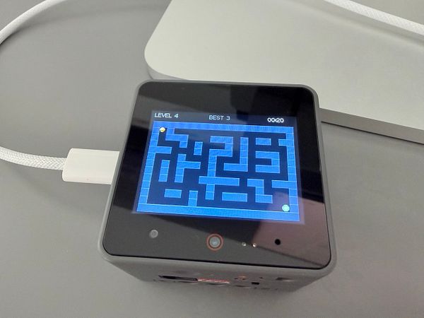 Top-down view of a mobile game with a ball and hole on a game board composed of various tiles.