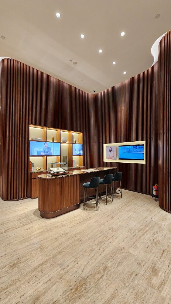 The image depicts the interior of a modern Rolex boutique featuring a sleek design with wooden accents and display screens.