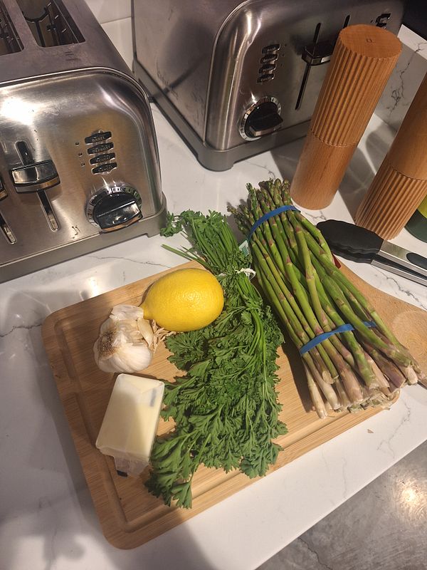 A wooden cutting board is arranged with ingredients for cooking pan-seared salmon.