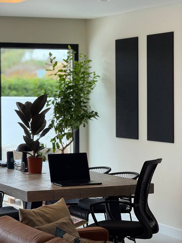A modern coworking space featuring acoustic tiles, plants, and a stylish table setup.