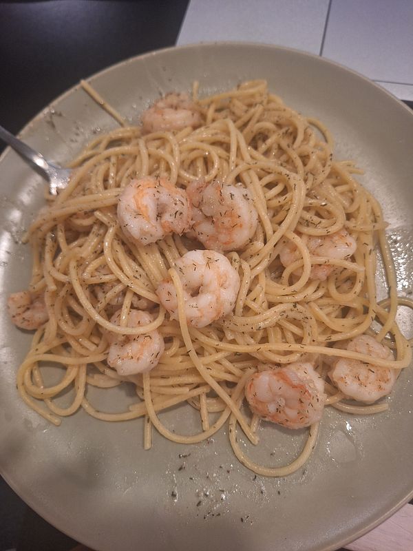 A plate of shrimp pasta is presented, showcasing a mix of spaghetti and shrimp.