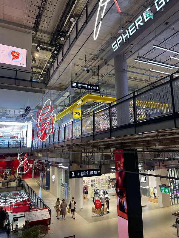A modern shopping mall interior featuring various stores and signage.