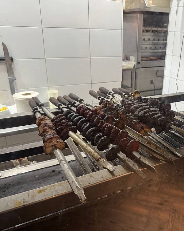 A display of skewered meats being grilled in a restaurant kitchen.