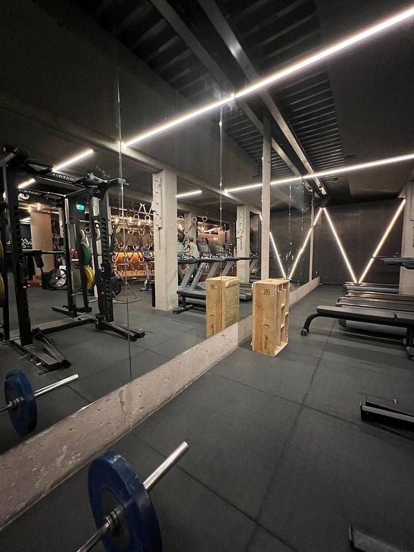 A modern gym interior featuring various workout equipment and a mirrored wall.