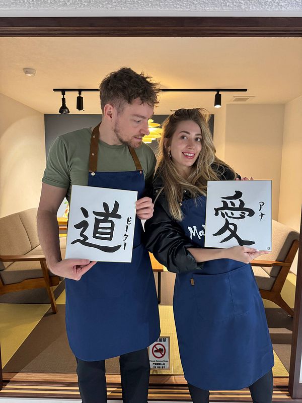 A couple poses with their calligraphy artworks in a Japanese calligraphy class.