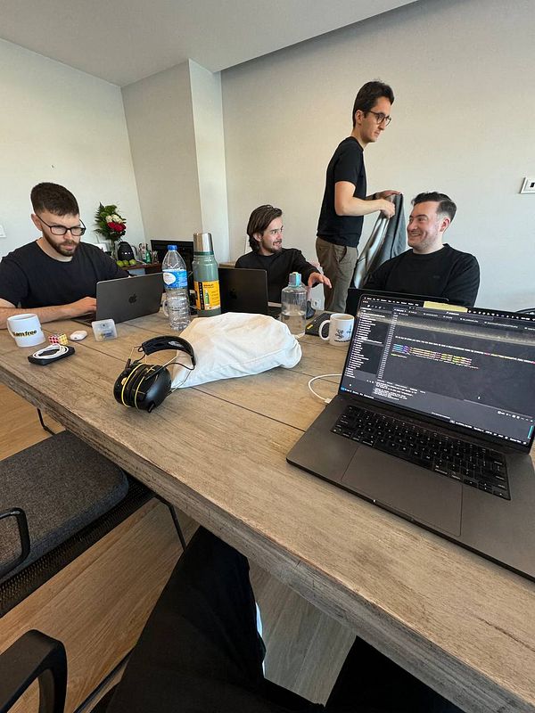 A group of four individuals is engaged in a collaborative coworking session at a wooden table.