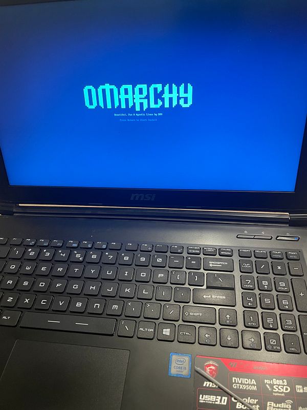 Laptop screen displaying Omarchy Linux installation boot screen with keyboard in view.