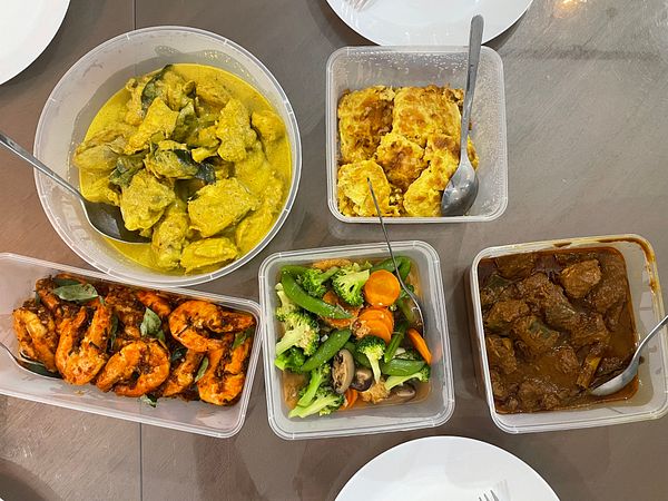 A spread of home-cooked dishes arranged in containers on a table.