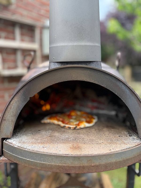 A pizza is baking inside a wood-fired oven.