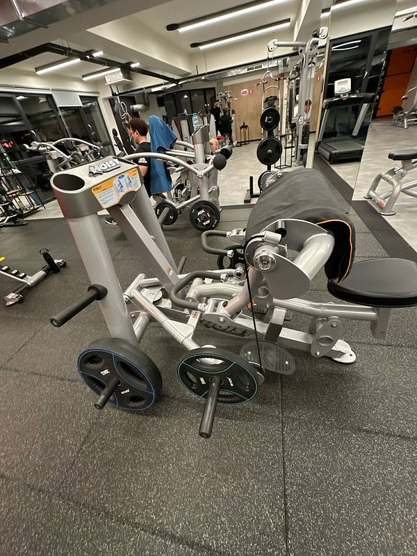 A gym setting featuring various exercise equipment, including a specialized machine for strength training.