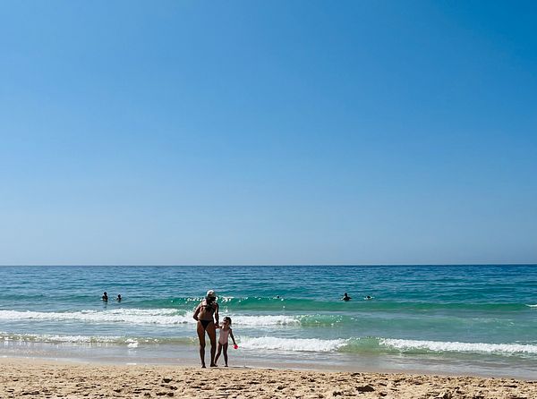 A woman and a child enjoy a sunny day at the beach.
