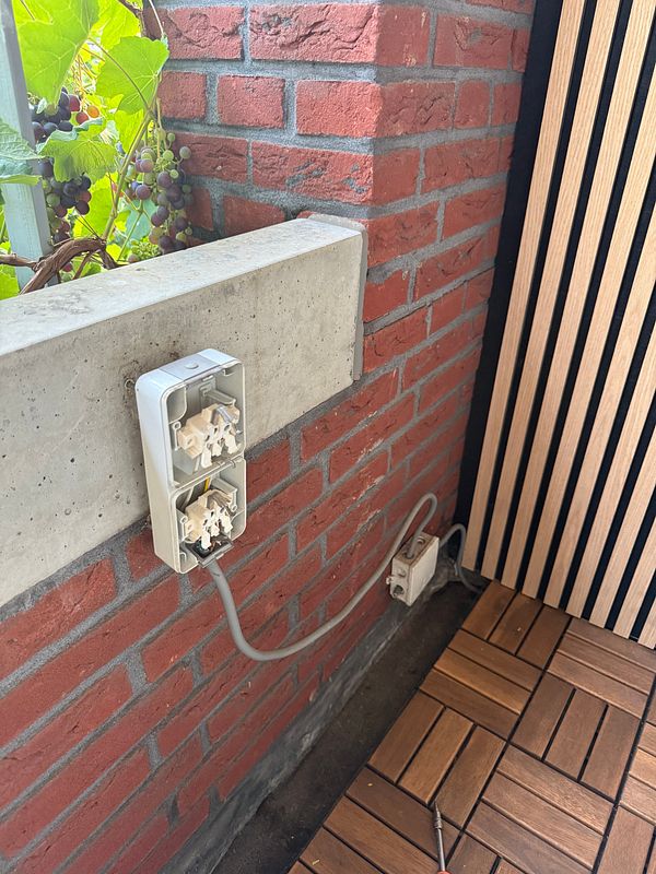 Close-up of electrical wiring and components inside a wall junction box undergoing repair.