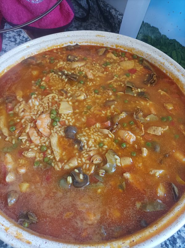 A vibrant seafood and vegetable paella is displayed in a large, shallow dish.