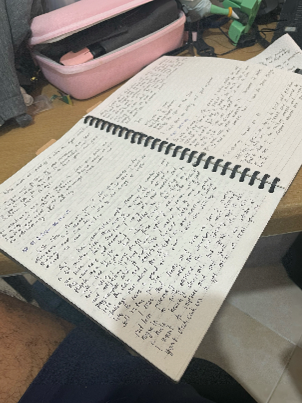 A neatly arranged journal page featuring dated entries, a wooden pen, and decorative elements such as leaves and a flower, set on a light wooden surface.