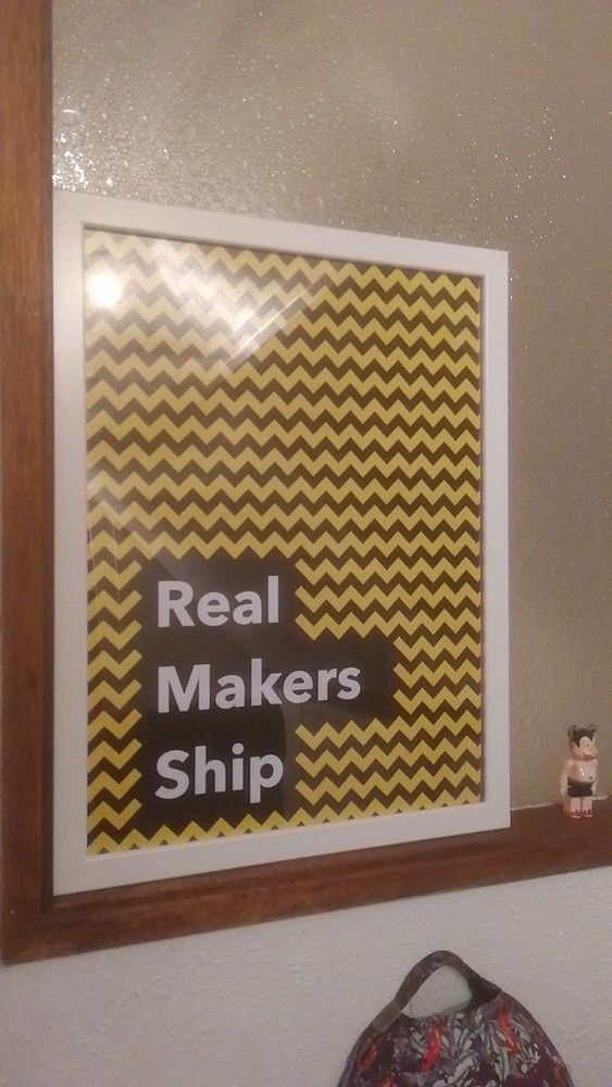 A framed poster with a zigzag pattern and bold text is displayed on a wall.