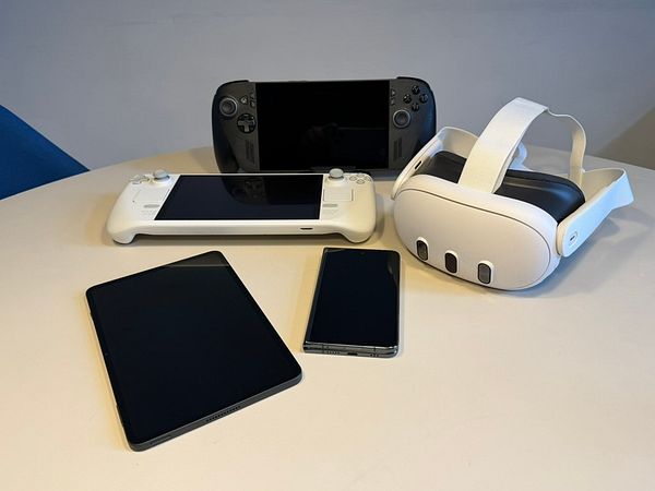 A Starbucks reusable coffee cup sits on a brown wooden table in an outdoor setting with green foliage and a bench in the background.