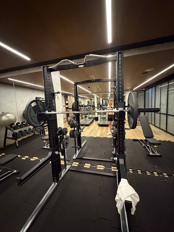 Modern hotel gym room in Warsaw with weightlifting equipment and a person taking a mirror selfie.