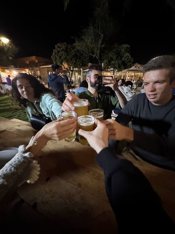 A group of friends is toasting with beers at a festival.