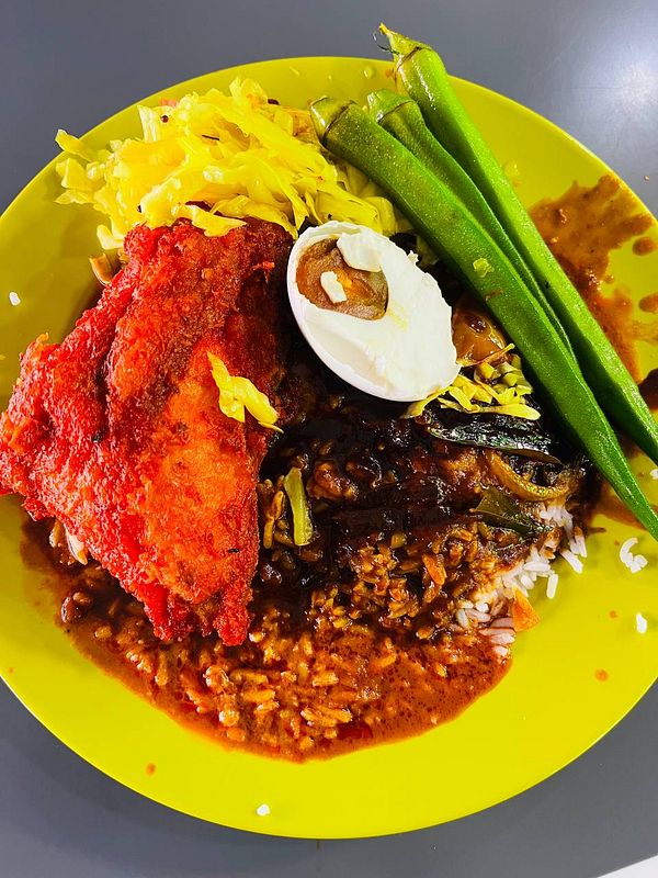 Plate of nasi kandar with various side dishes including curry, chicken, and vegetables on a banana leaf.