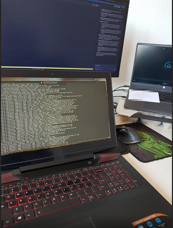A dual laptop setup with one laptop displaying terminal output and another showing a desktop interface.