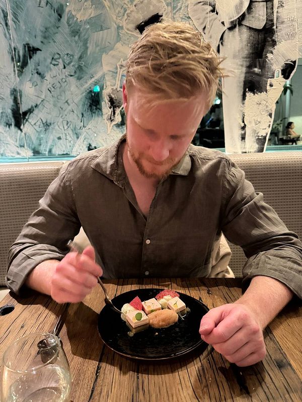 A man is seated at a restaurant table, preparing to eat a gourmet dish.