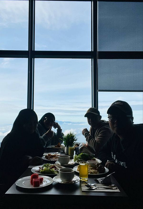 A group of four people enjoys a meal with a stunning view of the sky in the background.