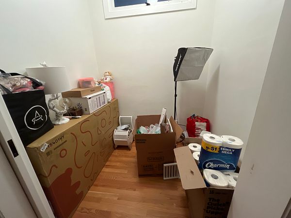 A small, clean, arranged room with wooden flooring and some furniture.
