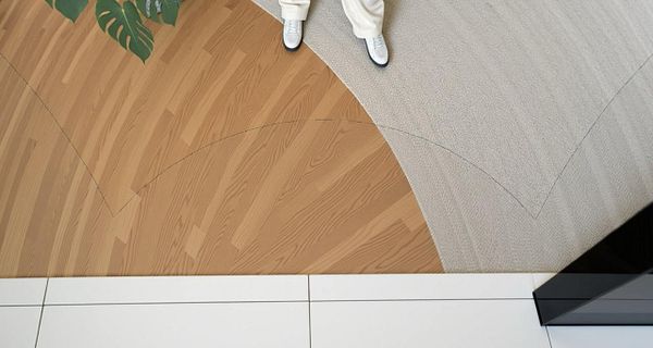A top-down view of a floor featuring different textures and colors, with a person standing on it.