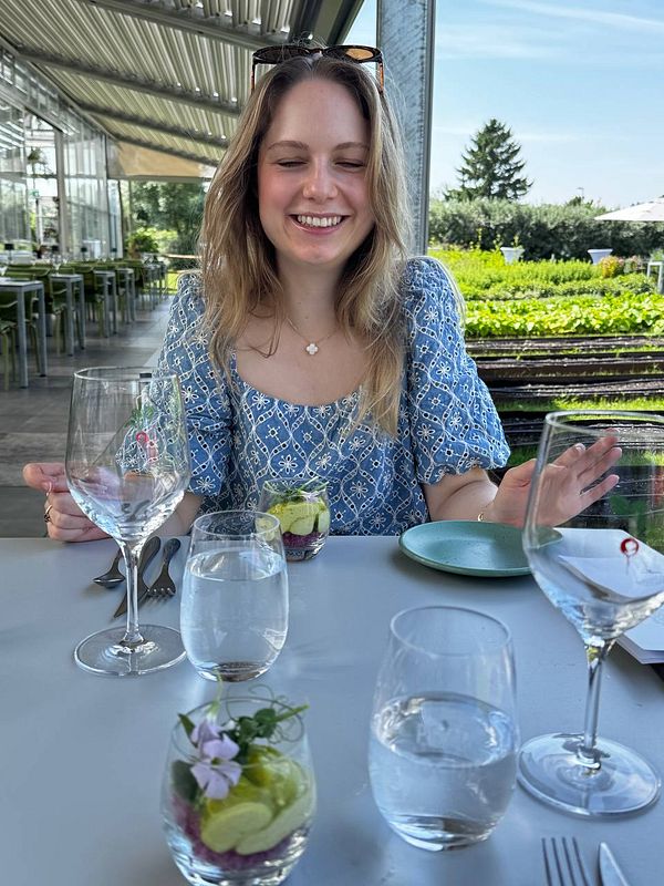 A cozy restaurant scene with a wooden table set for two, featuring a plate of fresh salad, wine glasses, bread, and silverware.