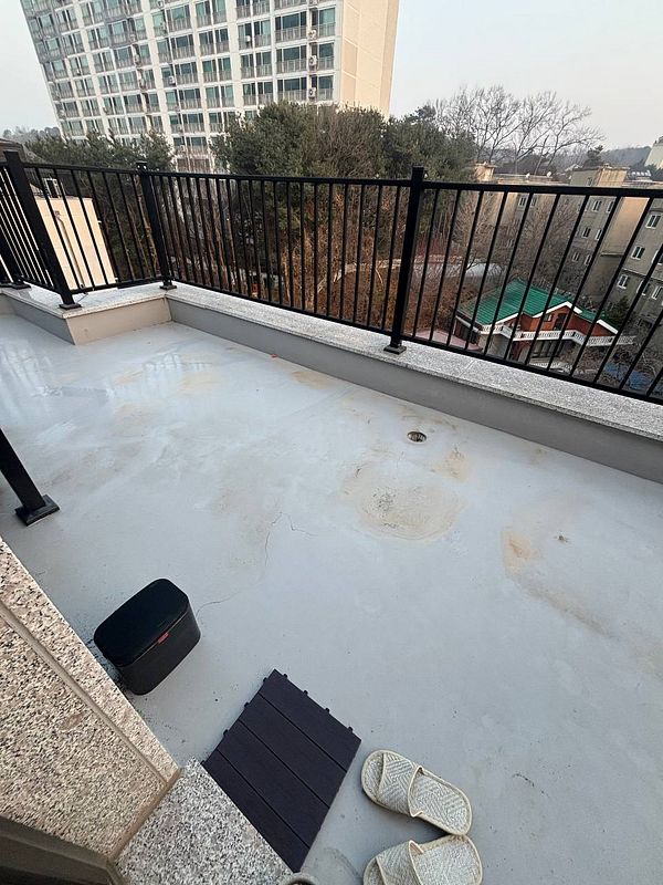 A balcony floor covered with newly installed wooden decking tiles arranged in a square pattern.
