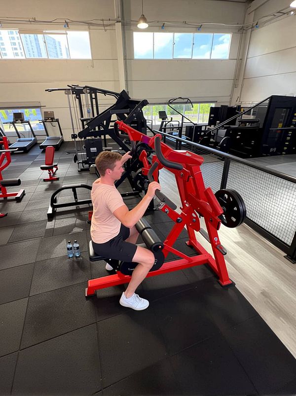 Portrait of a woman wearing a colorful patterned outfit, looking directly at the camera with a neutral expression against a white background.
