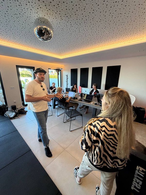 People collaborating and working in a modern co-working space with a disco ball ceiling fixture.